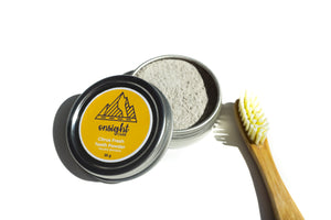 opened tooth powdered tin with bamboo tooth brush beside.