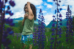 women applying zero waste deodorant bar on underarm in field of flowers and mountains.