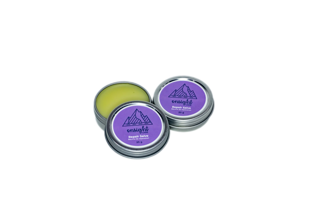 Repair Salve eco-friendly tins, open to reveal golden yellow balm. Purple labels on white backdrop.