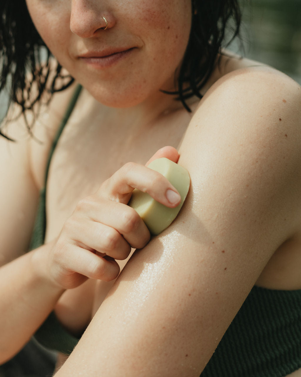 lady using naked solid lotion on bare skin with lake in the background